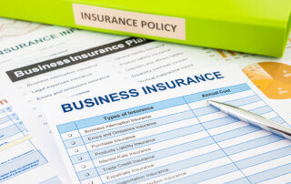 Documents on a desk. One document has the words "Business Insurance" as a title.