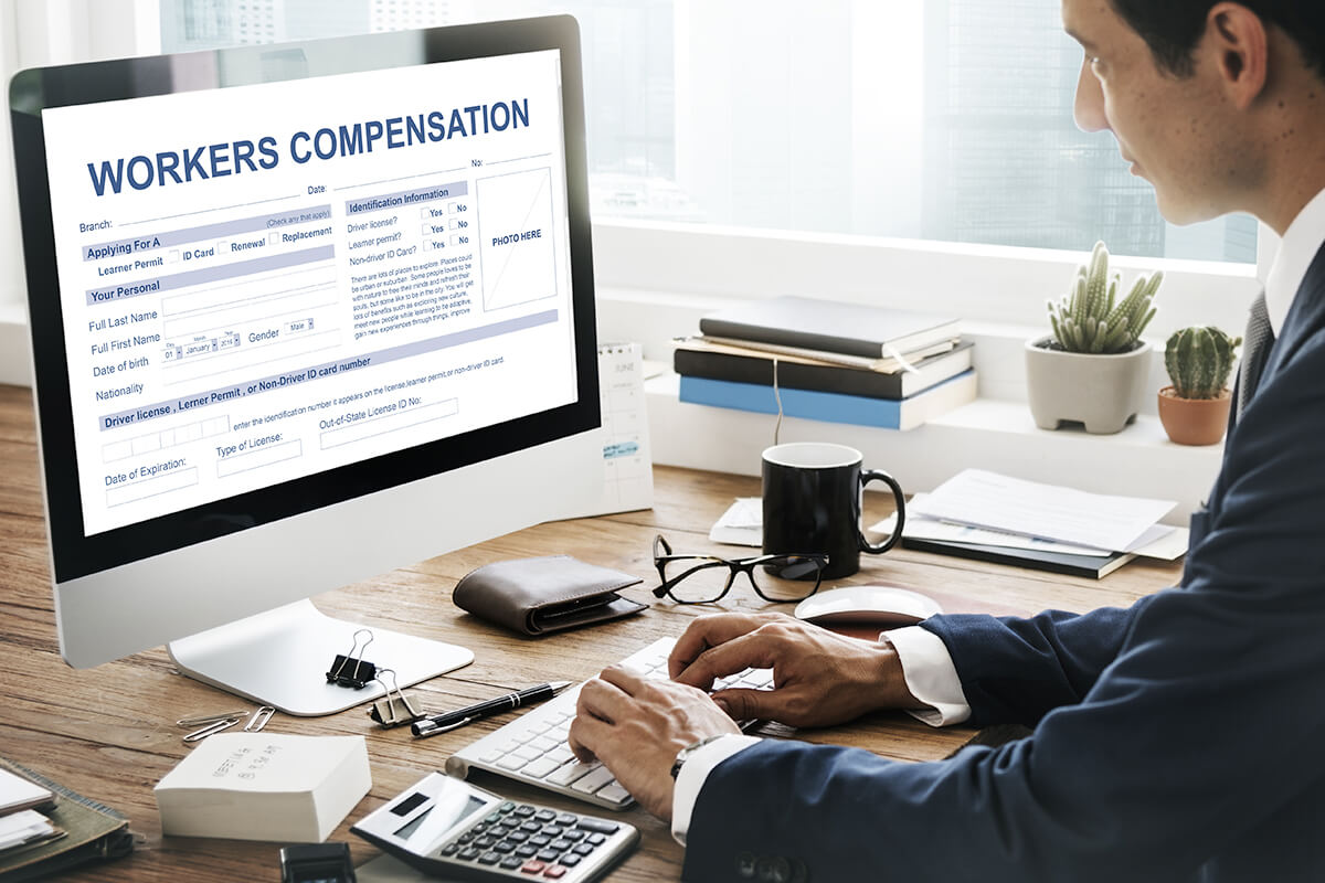 Worker looking at computer monitor with "workers compensation" forms displayed on the monitor.